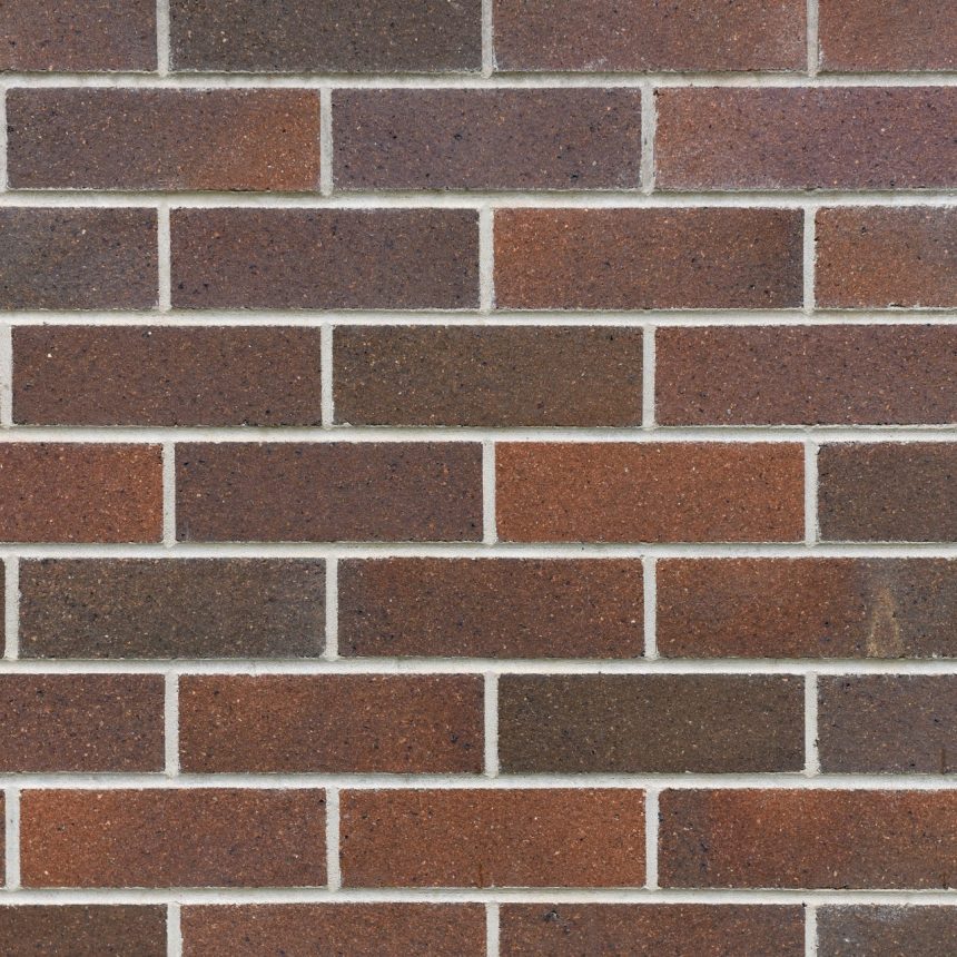 A close-up view of a brick wall highlights the Architectural Federation Red Blend, featuring a mix of brown and red hues arranged in horizontal rows. The bricks display subtle tonal variations, achieving a consistent yet textured look, while the light gray mortar complements this striking design.