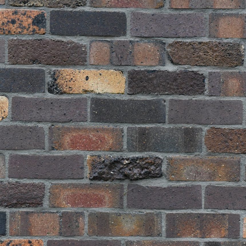 A close-up view of a wall showcases the Classic Dark Clinker Blend, featuring rectangular bricks in shades of brown, red, and black arranged in an elegant horizontal pattern. The texture and color variations evoke a rustic charm enhanced by the dark clinker undertones.