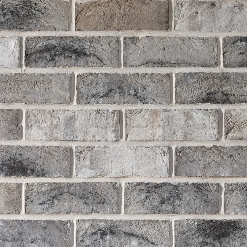 A detailed examination of the grey brick wall highlights the San Selmo Smoked Opaque Slate, showcasing its horizontal arrangement. The subtle differences in colour and texture contribute to a rustic, aged appearance, enriching the overall depth of the design.