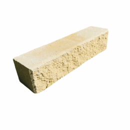 A single Broughton Garden Edge Basalt rectangular beige concrete brick, featuring a rough textured side, is displayed isolated on a white background.