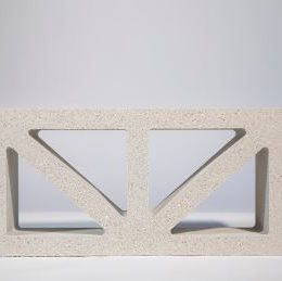 The Breeze Block Solid Grey, featuring a geometric pattern of triangular cutouts, sits on a light surface against a plain background, casting intriguing shadows along the edges of the cutouts.