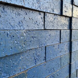 A close-up of blue Laguna Glazed Bricks shows visible texture and minor wear on each brick surface, with the bricks arranged in horizontal rows.