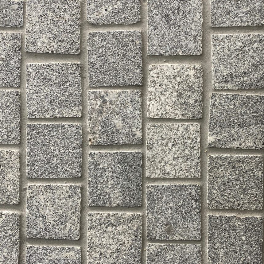 A close-up view of a wall made with Fantasy Grey Cobble showcases a grid pattern where the rectangular stones are neatly placed, highlighting visible grout lines. The surface offers a rough, natural texture.