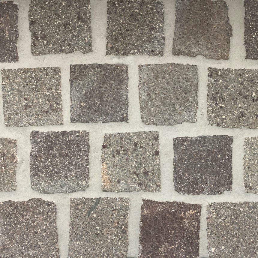 A floor composed of square cobbles from the Porphyry Loose Cobble collection, featuring textured grey stones arranged in a grid pattern. These stones have a rough surface and subtle shade variations, creating a natural and rustic look similar to loose cobble.