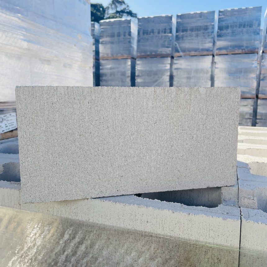 Piles of Smooth Face Opal White concrete blocks are showcased outside beneath a bright blue sky.
