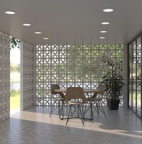 A modern room with floor-to-ceiling Cubic Astro White Breeze Blocks patterned walls and large windows letting in natural light. There is a round table with four wooden chairs and a potted plant in the corner. The floor is terrazzo, and recessed ceiling lights are on.