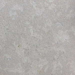 A close-up of a Sinai Pearl Acid Wash & Tumbled Paver reveals a light grey stone surface with subtle texture and natural patterns, giving it a gently weathered look reminiscent of limestone or concrete.