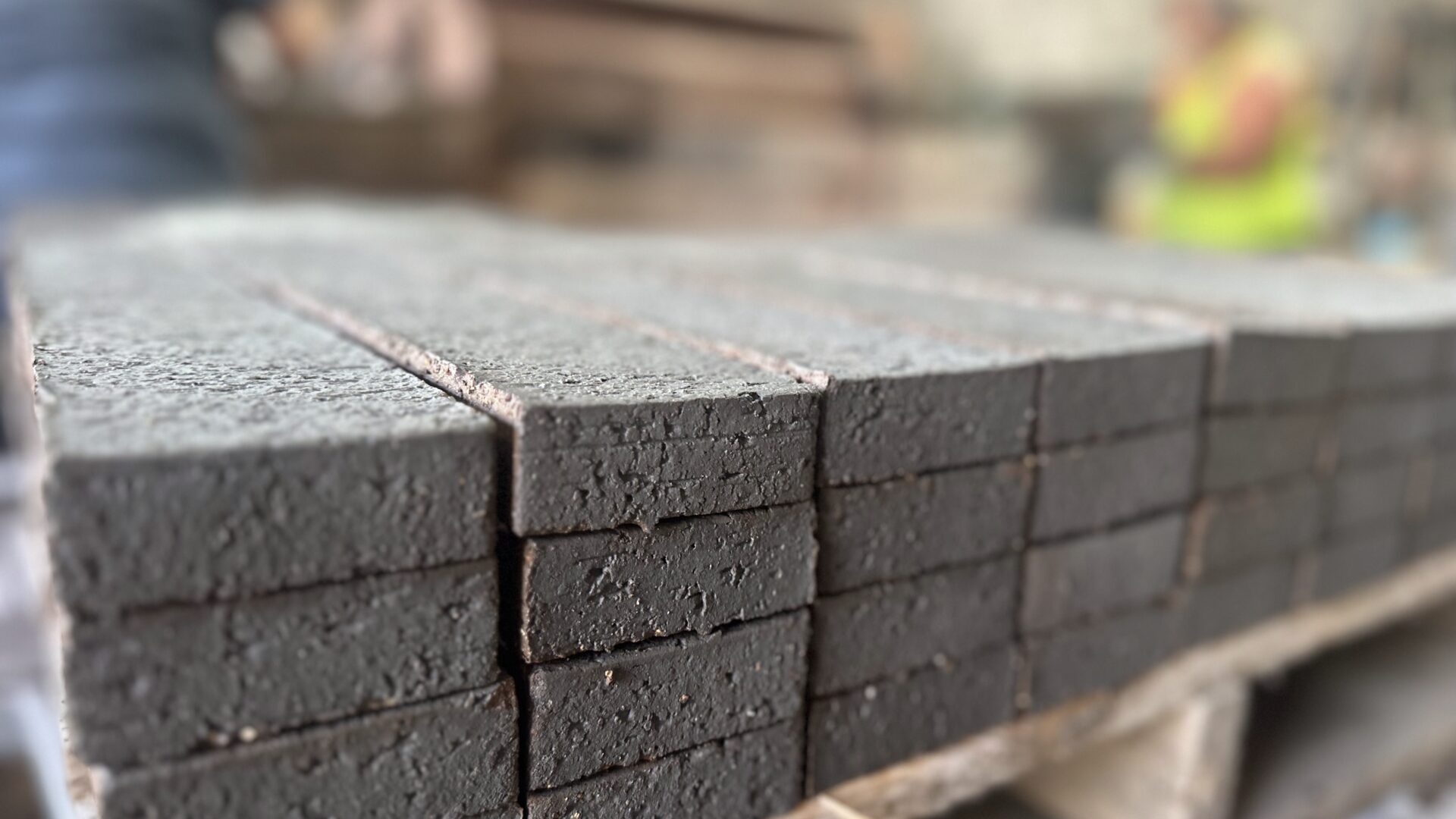 A stack of grey recycled bricks that have been cut into thin brick slips to create a lightweight brick cladding system.